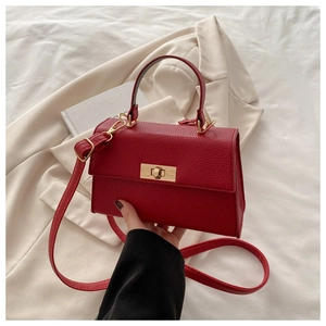 Detail of red lychee pattern leather bag with golden metal twist lock and top handle