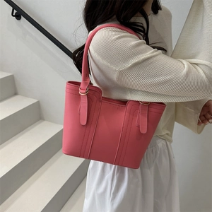 Pink faux leather bucket bag with vertical stitching and golden ring hardware on model