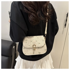 Dettaglio borsa a tracolla intrecciata beige con ricami floreali e chiusura dorata