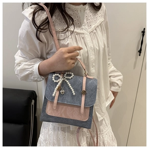 Detailed view of women's denim blue and pink handbag with pearl bow and heart charm