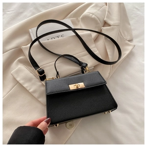 Close-up of black litchi pattern leather bag with gold twist lock and metal studs