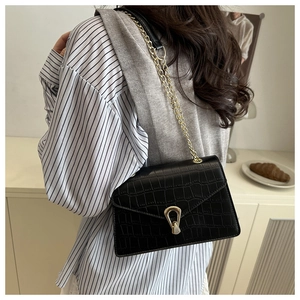 Detail view of black crocodile pattern bag with gold chain and heart-shaped metal clasp