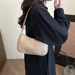 Minimalist beige woven hobo shoulder bag with textured faux leather on a model