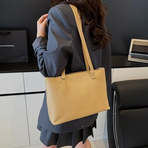 Grand sac cabas jaune clair avec surpiqûres blanches présenté dans un cadre de bureau moderne