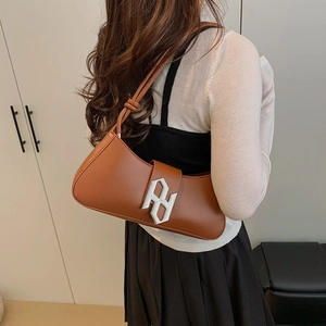 Caramel brown leather baguette bag with silver buckle worn by model in minimalist setting