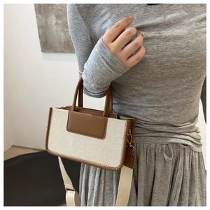 Detail of contrast stitch tote bag featuring premium canvas and brown leather handle