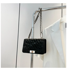 Détail du cuir noir matelassé et de la chaîne dorée sur ce sac à bandoulière tendance