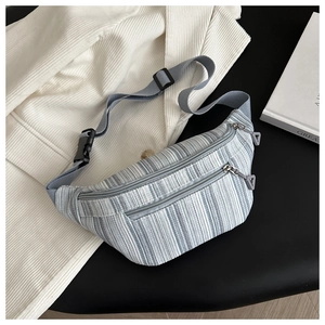 Detail of striped corduroy waist bag showing multi-zipper layers and woven strap