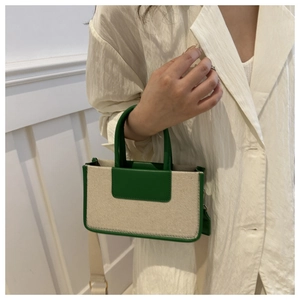 Detail of a green and beige crossbody bag with contrast handles and adjustable strap