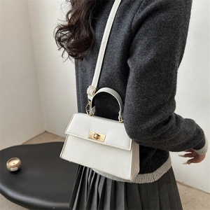 White lychee pattern small crossbody bag with gold twist lock on stylish gray knitwear
