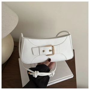 Detail der weißen minimalistischen Untertasche mit Goldschnalle und Knotenschultergurt