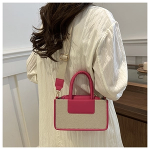 Detail view of beige canvas small square bag with vibrant pink leather trim and wide strap
