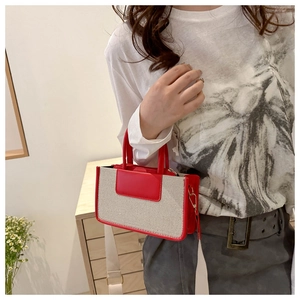 Detail of red and beige patchwork canvas mini tote bag worn by model in home setting