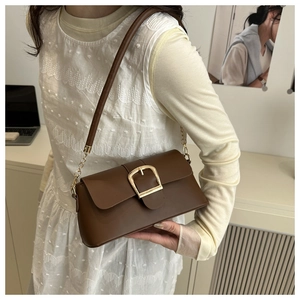 Borsa a spalla retrò in pelle marrone con fibbia dorata indossata da una modella