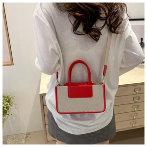 Detail of a minimalist canvas and red leather small square bag with a woven shoulder strap
