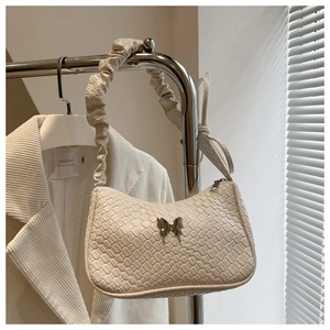 Detail of woven texture bag with silver butterfly charm and ruched handle detail