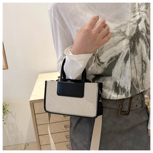 Detail of canvas mini tote bag with black leather trim and detachable wide strap