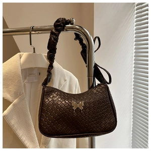 Detail of dark brown woven shoulder bag featuring a silver butterfly metal buckle