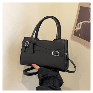 Detail of black leather handbag with bow decoration and adjustable silver buckle strap