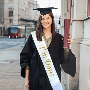 White satin graduation sash with gold foil I'm Done text worn with academic regalia