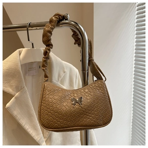 Detailed view of brown woven handbag with silver butterfly buckle and pleated strap