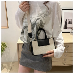 Detail of color-block canvas and leather handbag with wide crossbody shoulder strap