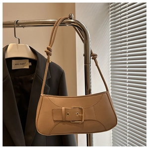 Detail der beige Schultertasche mit Schnalle und geknotetem Riemen am Kleiderbügel