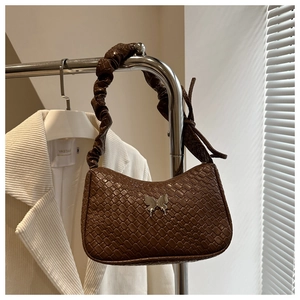 Detail of brown woven hobo bag with scrunchie strap and silver butterfly accent