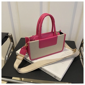 Detail of a pink leather and canvas handbag featuring golden hardware and a woven strap