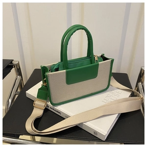 Detail of green leather and canvas contrast stitching on a square crossbody handbag