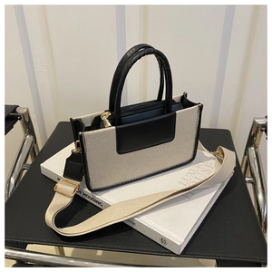 Detail of a beige woven tote bag with black leather trim and detachable wide strap