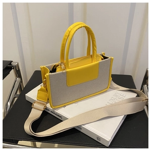 Detail of a bright yellow and grey canvas tote bag with a wide detachable shoulder strap