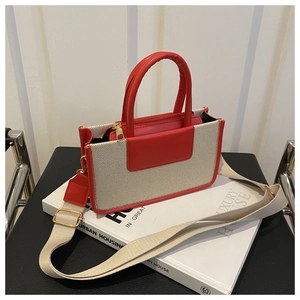 Detail of contrast color crossbody bag with red leather handles and cream canvas texture