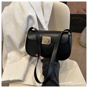 Detail of a black crescent shoulder bag featuring a square gold buckle on a white texture