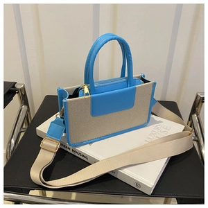 Detail of blue leather and canvas patchwork bag with detachable beige woven shoulder strap