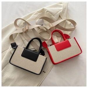 Detail of canvas crossbody bag featuring contrasting leather trim and woven texture
