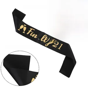 Detail of black satin sash featuring gold foil Finally 21 text and champagne pattern