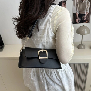 Borsa a tracolla minimalista in pelle nera con fibbia a U dorata portata a spalla