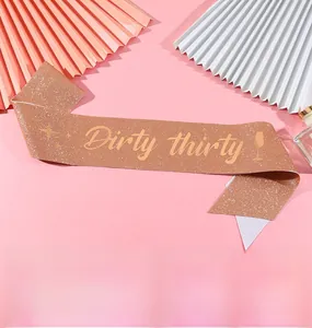 Detail of rose gold glitter sash with Dirty Thirty font and party icons for 30th birthday