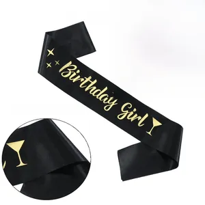 Macro detail of the gold stamped Birthday Girl text on a black satin party sash ribbon