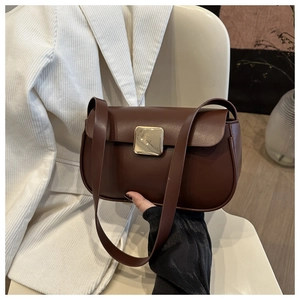 Detail of dark brown leather handbag with luxury gold square buckle and textured surface