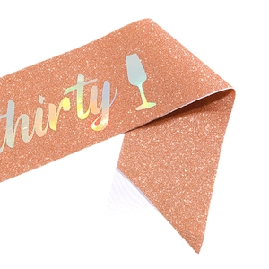 Close-up of rose gold glitter birthday sash with holographic Thirty text and wine glass