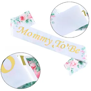 Détail de l'écharpe Mommy To Be avec motifs floraux roses et lettrage doré pour baby shower