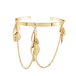 Detailed view of gold leaf arm cuff with dangling tassels on a white background