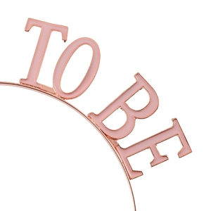 Detail of rose gold Mommy To Be headband featuring elegant pink enamel lettering