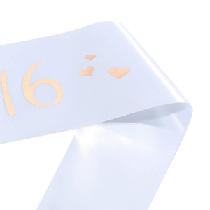 Close-up of white satin birthday sash with rose gold 16 and heart patterns