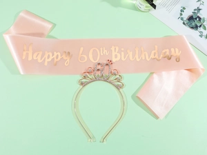 Macro shot of 60th birthday set with rose gold satin sash and sparkling rhinestone tiara