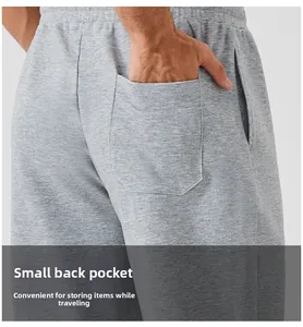 Detail of light grey joggers featuring a functional back pocket and smooth cotton texture