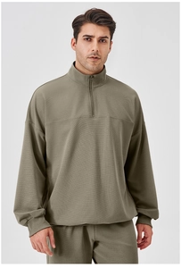 Front view of men's olive green sports sweatshirt with textured fabric and half-zip collar