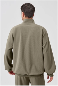 Men's olive green sports tracksuit detail showing ribbed cuffs and drop shoulder seam